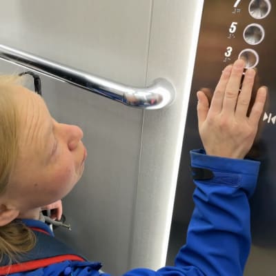 Sirpa Myöhänen etsii oikeaa hissinappulaa sormenpäillään.