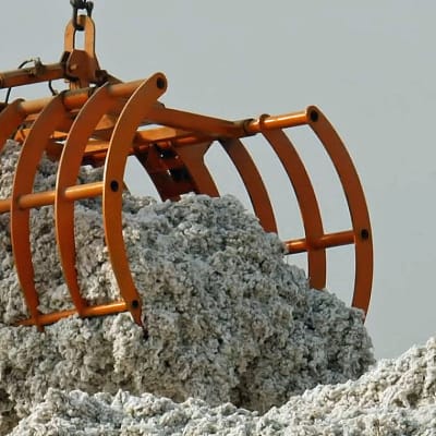 En stor orange griplastare lyfter fluffig grå råbomull.