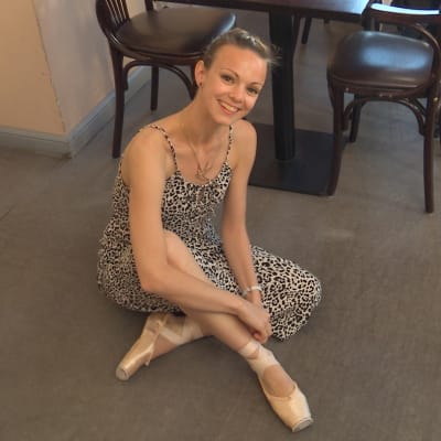 Ballerina Claire Voss sitter på ett cafégolv, brevid sig har hon sin tutu.