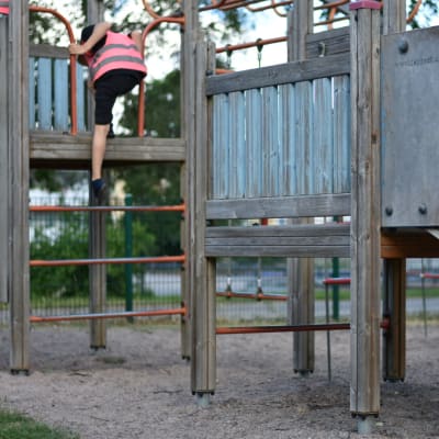Lapsi kipuamassa ylös kiipeilytelineellä leikkipuistossa. 