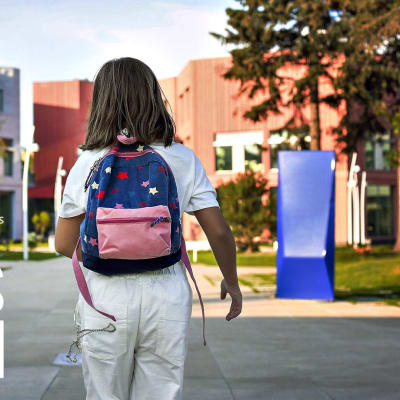 Photo shows a child walking towards a school, with the All Points North logo in the left hand corner.