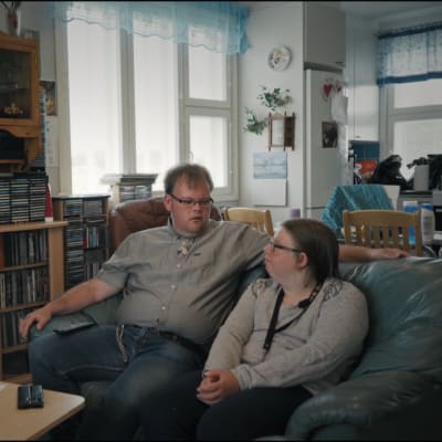 Två personer, Anders och Cecilia, sitter bredvid varandra i en mörkgrön lädersoffa.