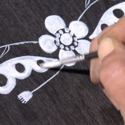 med pensel målas en grafisk bild av en blomma och ett ornament