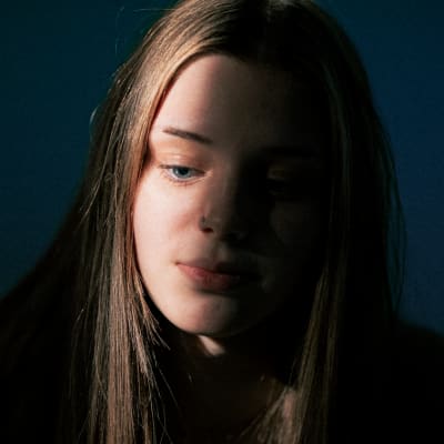 Julietten kasvoihin osuu valojuova ja hän katsoo alaspäin lähikuvassa.