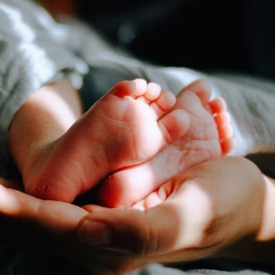 Vauvan jalkoja pidellään kämmenen päällä.