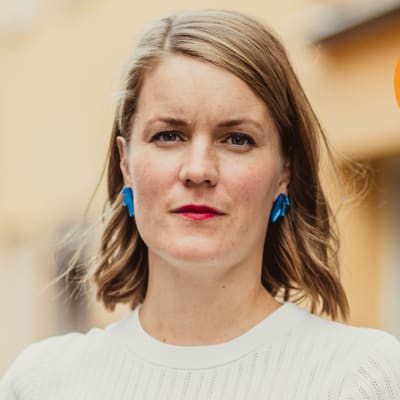 Marianne Sundholm framför ett gul-oranget hus.