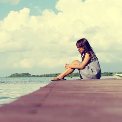 en flicka sitter ensam på en brygga