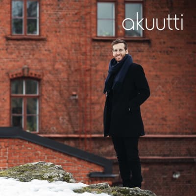 Positiivisen pedagogiikan tutkija Kaisa Vuorinen ja psykologi Jaakko Sahimaa seisovat vanhan punatiilisen rakennuksen edustalla ja hymyilevät kameralle.