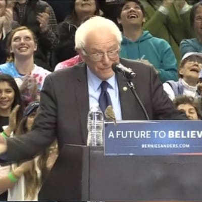 Pikkulintu istuu puhujanpöntöllä Bernie Sandersin edessä.