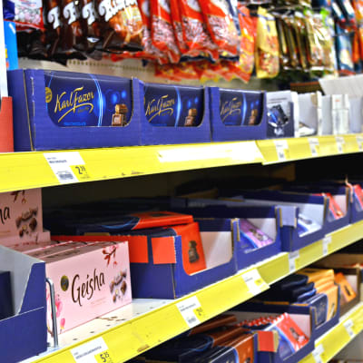 Kuvassa kaupan karkkihylly, jossa näkyy suklaata ja karkkipusseja.