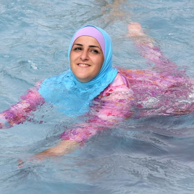Nainen uimassa burkini-uimapuvussa.