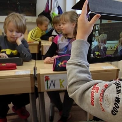 Oppilas ottaa iPadilla kuvaa luokkakavereistaan.