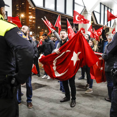Kaksi poliisia ja lukuisia turkin lippua heiluttavia mielenosoittajia.