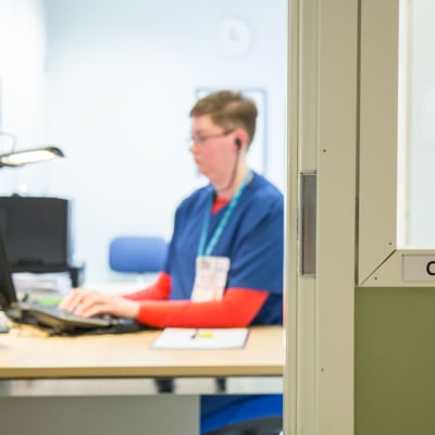 Osastonsihteeri Minna Romppainen istuu työpisteellään Kainuun keskussairaalassa.