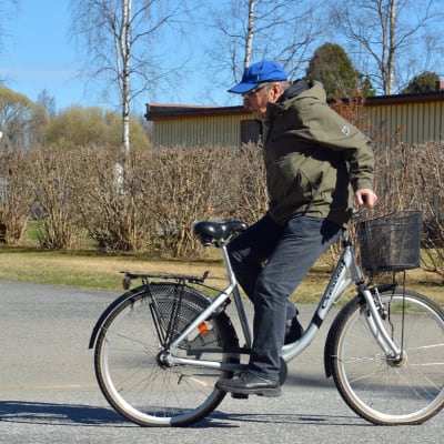 Mies ajaa polkupyörällä selkä menosuuntaan päin.