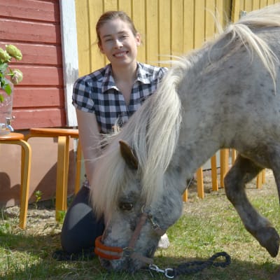 Liisa Koivisto hevosen kanssa tallin edustalla