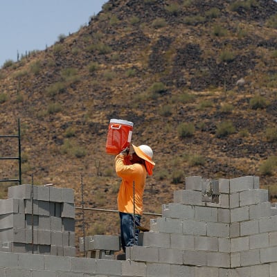 Mies juo vettä äärimmäisessä helteessä rakennustyömaalla Phoenixissa, Arizonassa.