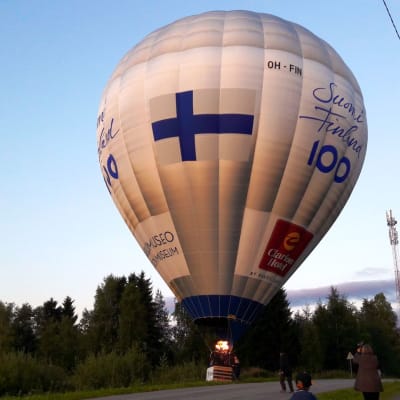 Suomi 100 -kuumailmapallo maantiellä.