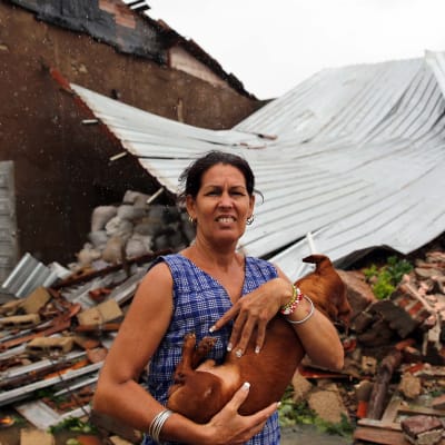 Nainen piteli koiraansa sylissään tuhoutuneen kotitalonsa edustalla Remedioksen kaupungissa Kuubassa 9. syyskuuta. 