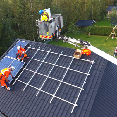 Miehiä asentamassa aurinkopaneeleja katolle.