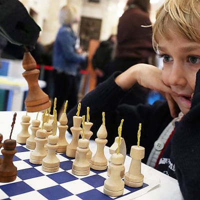 Pieni poika pelaa shakkia robottia vastaan tiedemessuilla 6.10. Moskovassa.