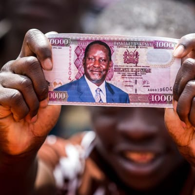 Mies pitelee kädessään Odingan kuvalla varustettua, väärennettyä 1000 shillingin seteliä.