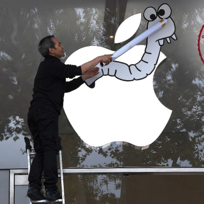 Aktivisti kiinnittää matoa Applen omena-logoon Ranskassa.