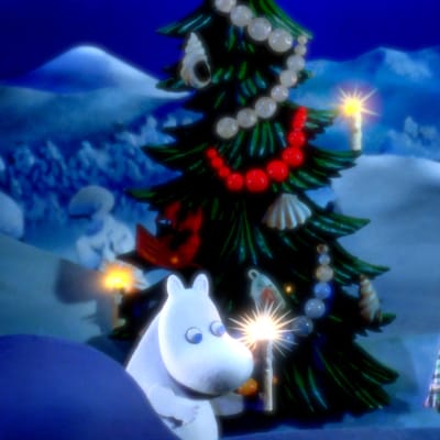 Mumintrollet står ute vid en pyntad julgran och håller i ett ljus, bredvid står hans föräldrar insvepta i en filt.