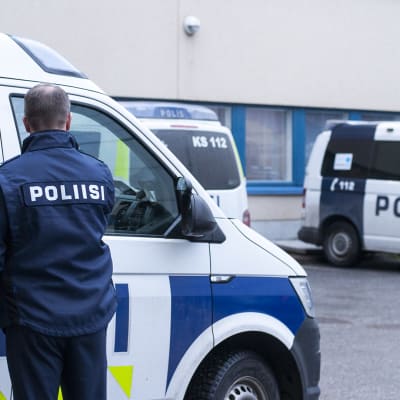 Poliisi menossa autoonsa ja taustalla lisää poliisiautoja