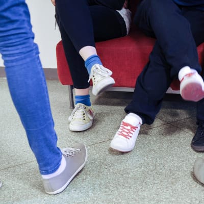Oppilaita koulun käytävällä, kuvassa nuorten kenkiä. 