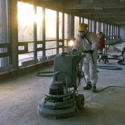 Mies poistaa asbestia rakennustyömaalla.