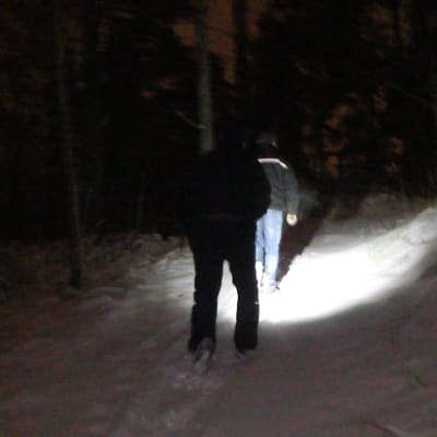Två personer går i en mörk skog.