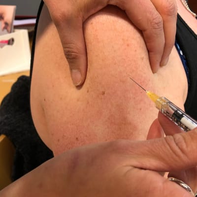 Kuvassa nainen saa rokotteen olkavarteen