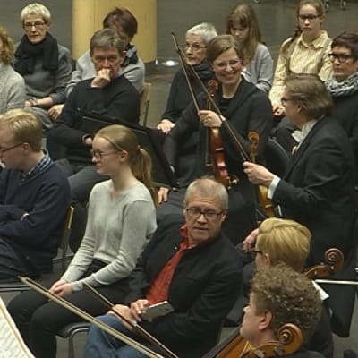 Yleisö istuu orkesterin keskellä konsertissa