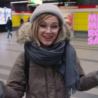 Ronja Salmi katsoo kameraan ja levittää käsiään metrotunnelissa