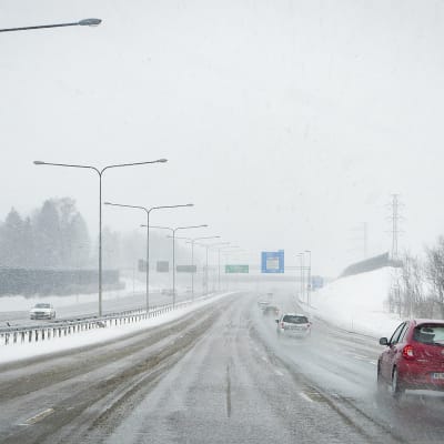 Autoja ajaa lumisateessa.