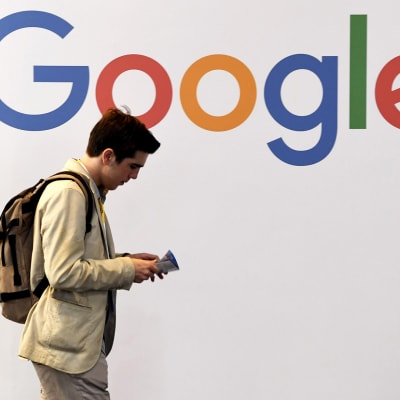 Mies kävelee Googlen logon edessä.