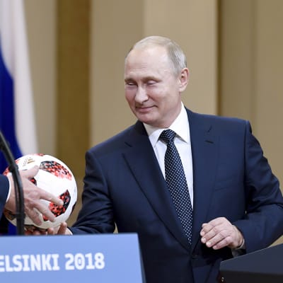 Vladimir Putin ojentaa jalkapallon Donald Trumpille tiedotustilaisuudessa Helsingissä.