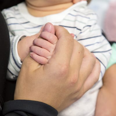 Äiti pitelee kädestä vastasyntynyttä vauvaa sairaalassa.