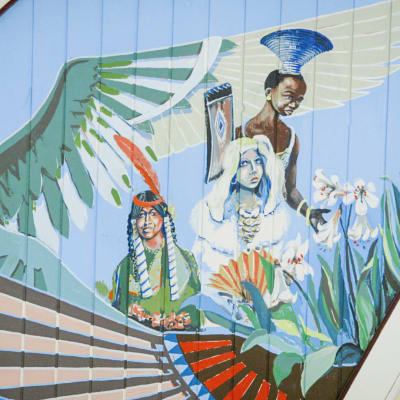 Kirkasvärisiä maalauksia kirkon katossa, papukaija, eri etnisiä ryhmiä edustavia enkeleitä.