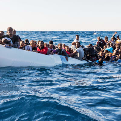 Siirtolaisia kumiveneessä meressä.