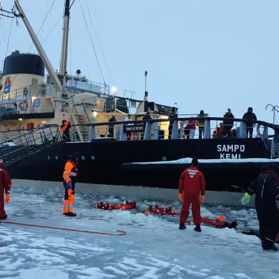 Jäänmurtaja Sampo pysähdyksissä Perämerellä kun turistit kelluvat meressä.