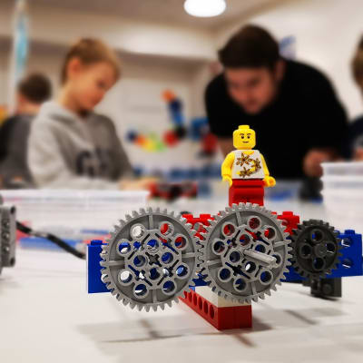 Legoista rakennettu kone ja takana ihmisiä.