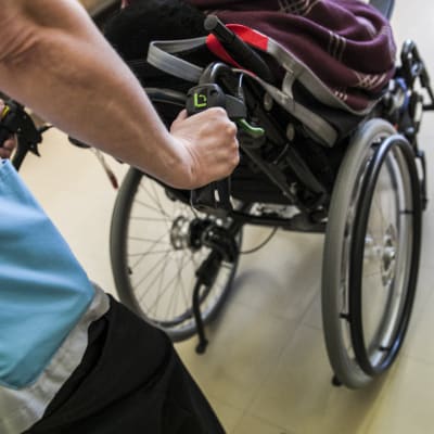 Hoitaja työntää vanhusta pyörätuolissa Tervossa hoivakoti Vuokossa.