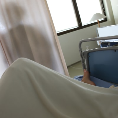 Potilas makaa potilashuoneen sängyllä.