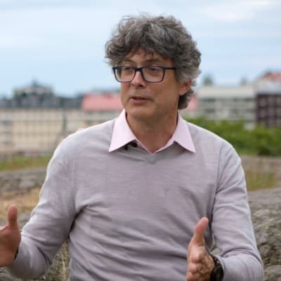 Per Espen Stoknes sitter på en klippa och berättar