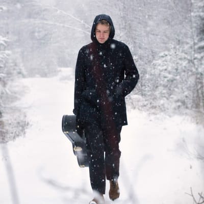 Lauluntekijä Topi Saha kävelee lumisella metsätiellä.