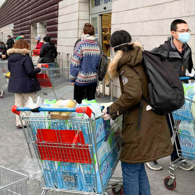 Ihmiset jonottavat ostoksille supermarkettiin Milanossa.