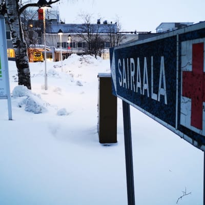 Sairaalakyltti Länsi-Pohjan keskussairaalan edessä. Takana sairaalan edessä näkyy ambulanssi. 