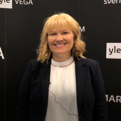 Johanna Törn-Mangs står framför en svart vägg med vit Svenska Yle-logga på.